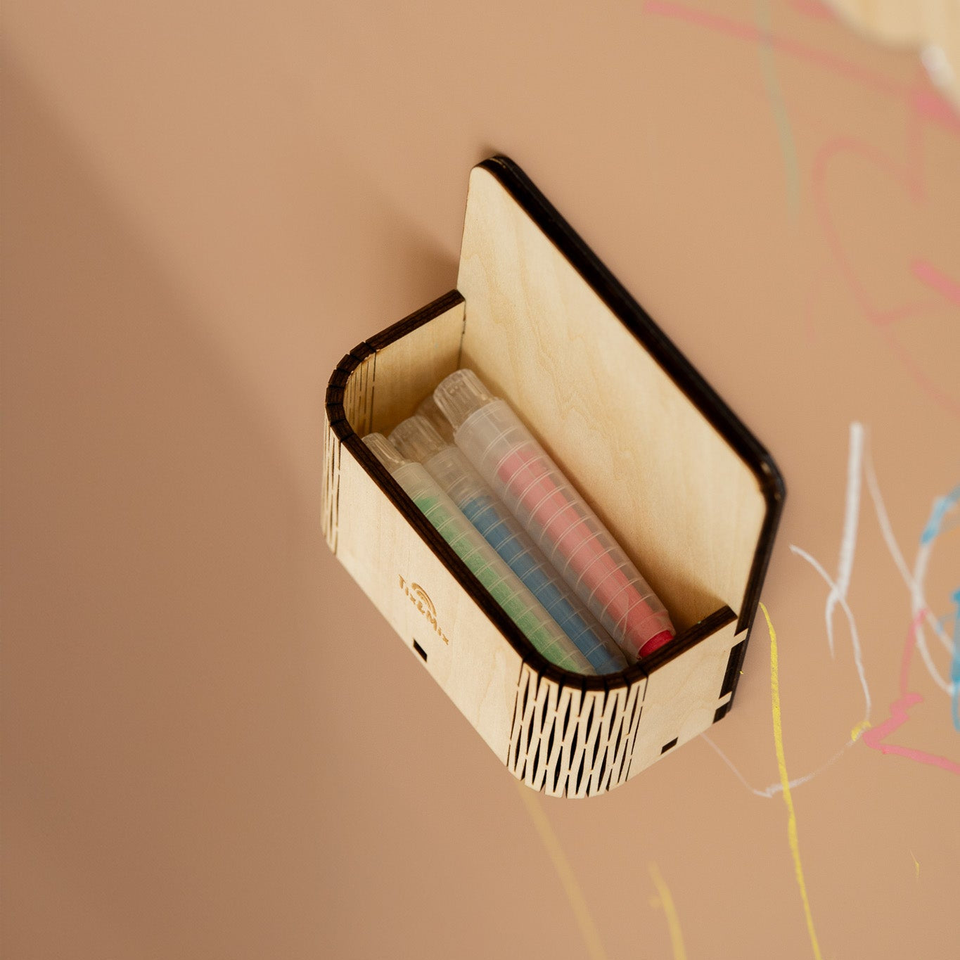 Small wooden box with colorful markers on a beige background