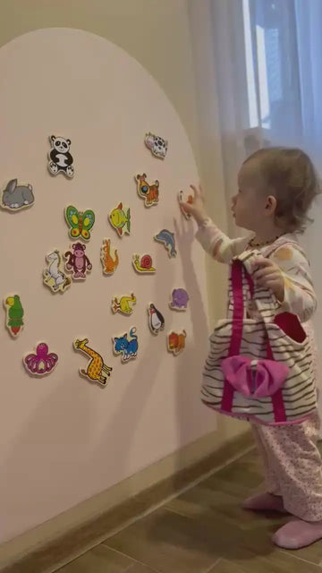 A child playing with Tix&Mix magnetic animal toys on a magnetic wall decal.