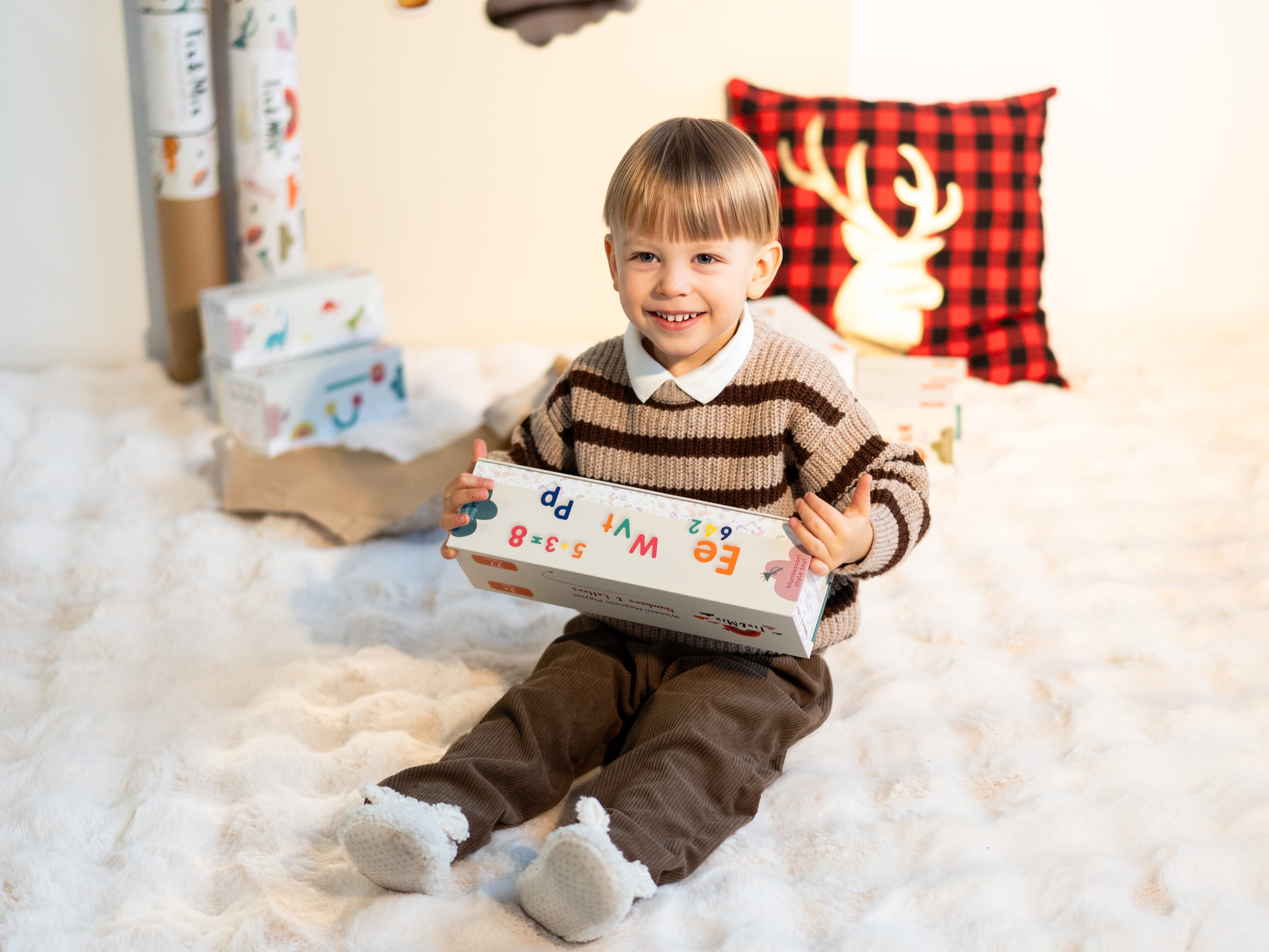A child smiling while holding a Tix&Mix magnetic play set in a box.