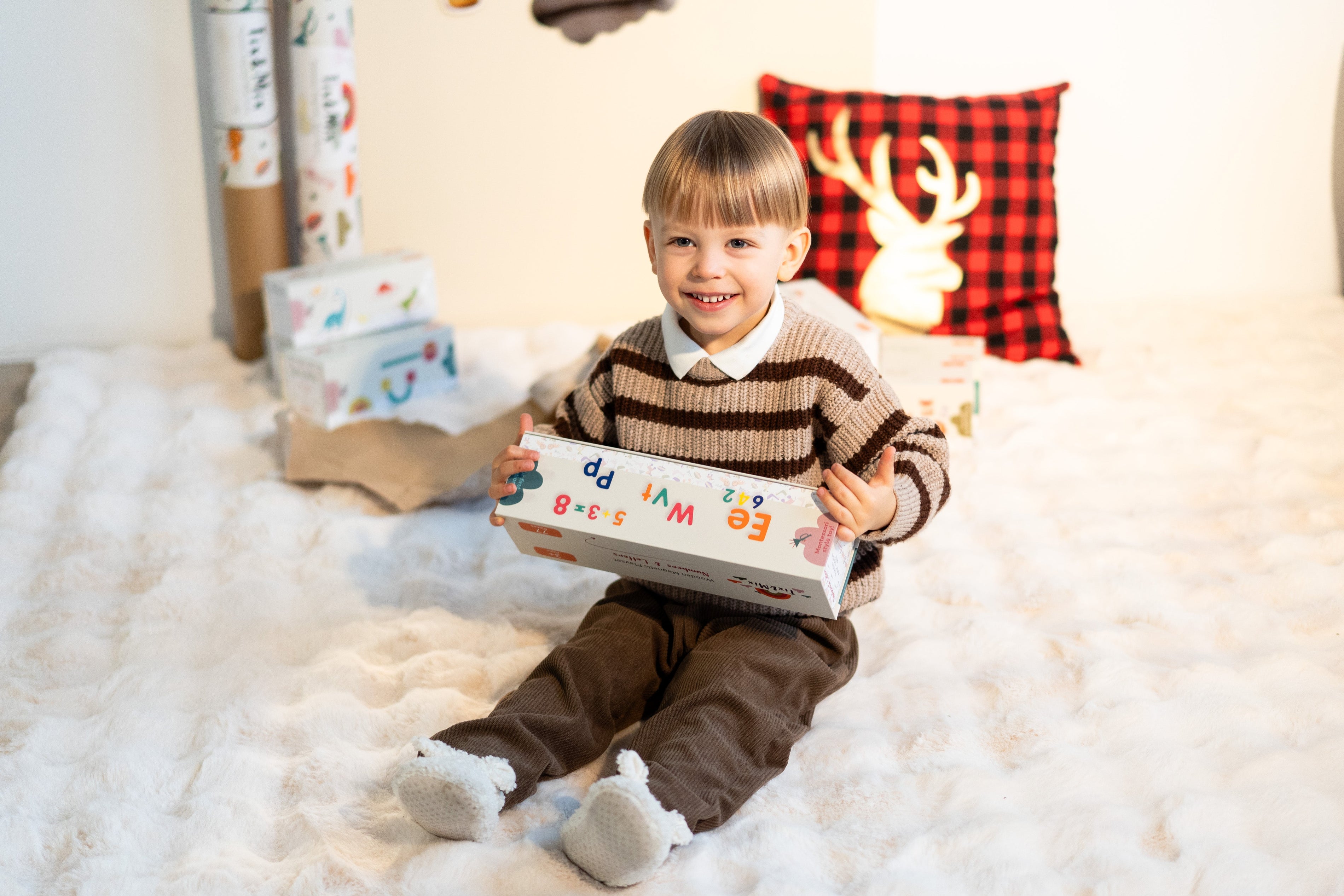 A child smiling while holding a Tix&Mix magnetic play set in a box.