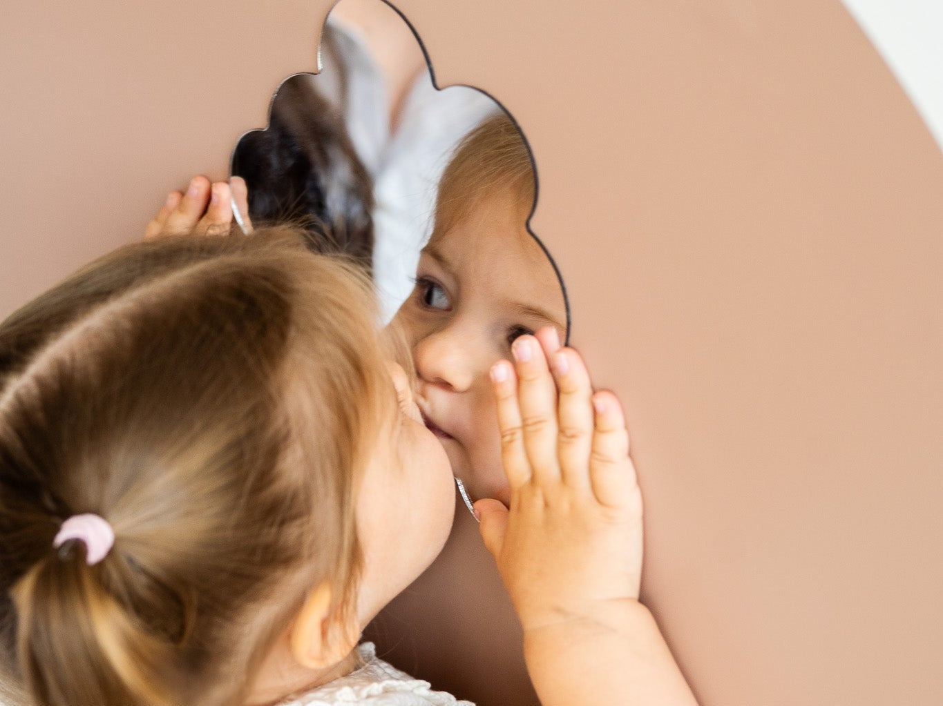 A kid looking at herself on a magnetic mirror placed on a magnetic wall board.
