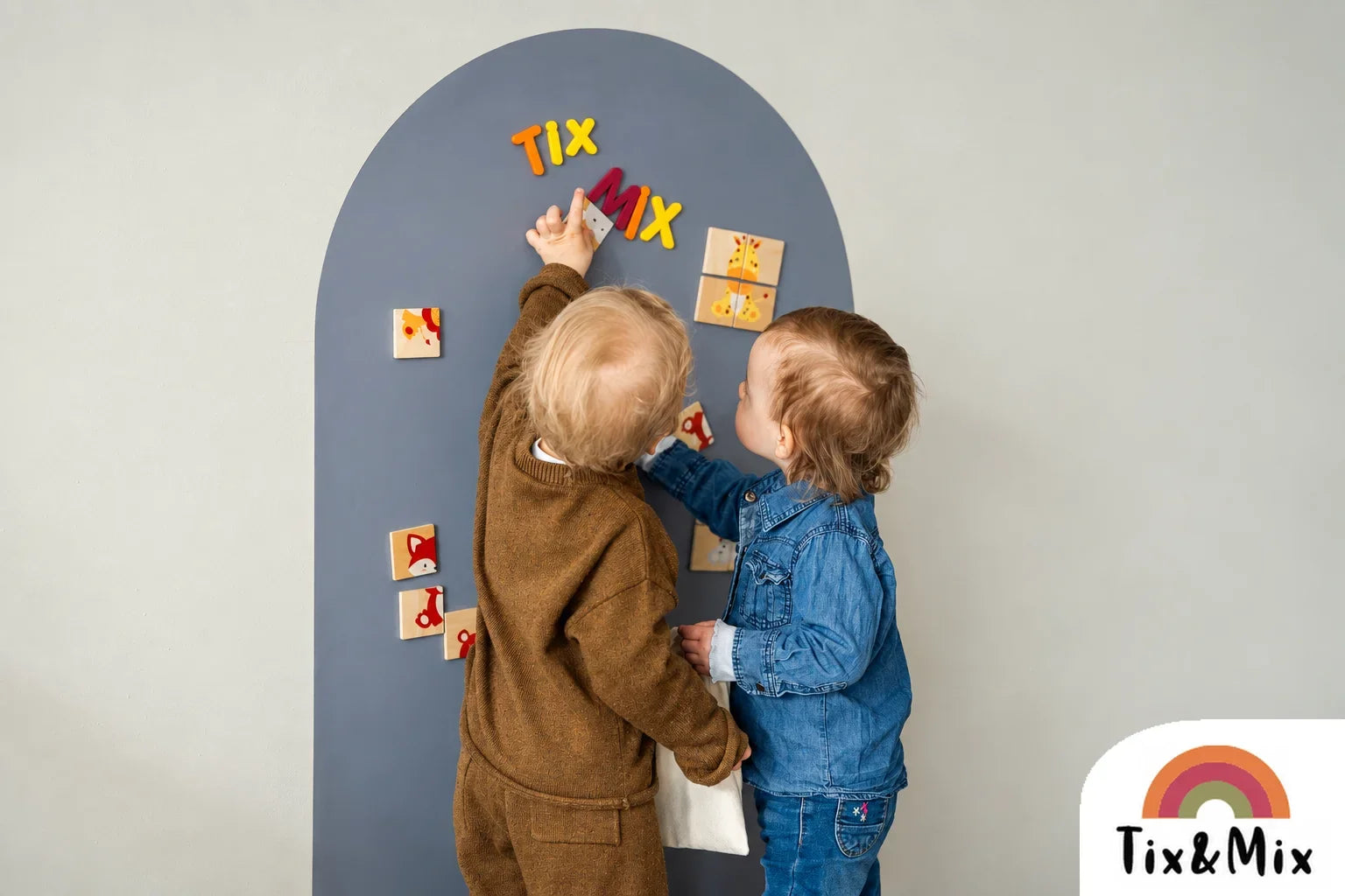 Two children playing together on a grey Tix&Mix magnetic wall board.