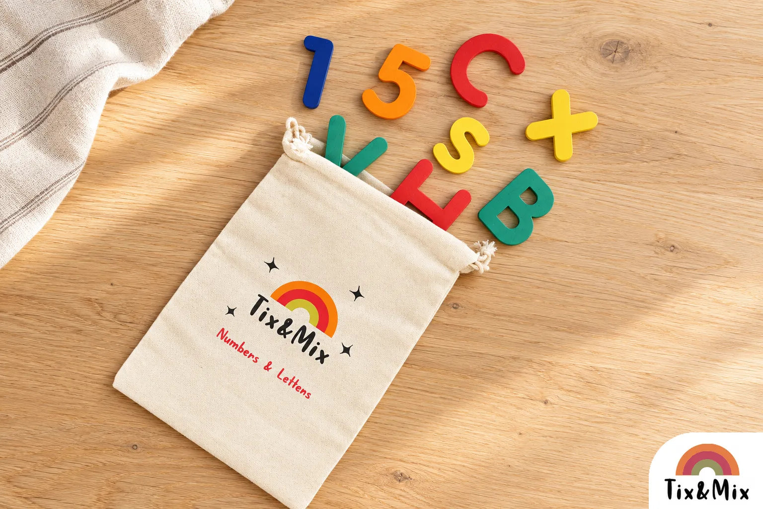 Colorful Tix&Mix wooden magnetic letters, numbers, and symbols spilling from a cotton storage pouch onto a wooden table.