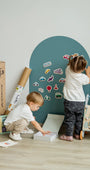 Two toddlers playing with Tix&Mix wooden magnetic vehicles playset on a cyan wave magnetic wall decal.