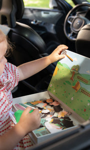 A female kid playing with Tix&Mix magnetic play box Farm Zone inside a car.