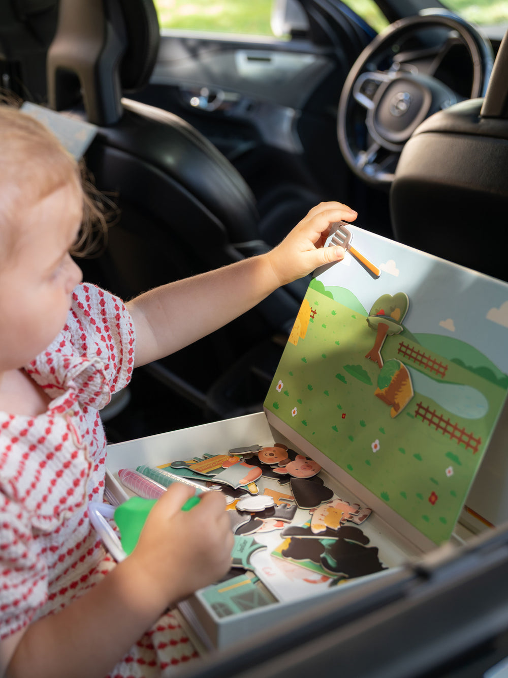 A female kid playing with Tix&Mix magnetic play box Farm Zone inside a car.