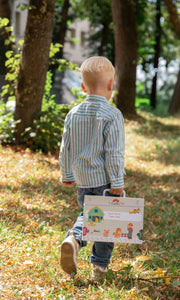 A male kid walking outside while holding the Tix&Mix magnetic play box magnetic farm zone set.