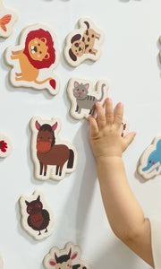 A kid playing with Tix&Mix wooden magnetic animals playset on a white wall decal.