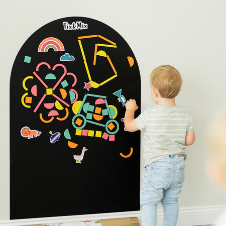 A male toddler playing on a Tix&Mix black magnetic wall decal.