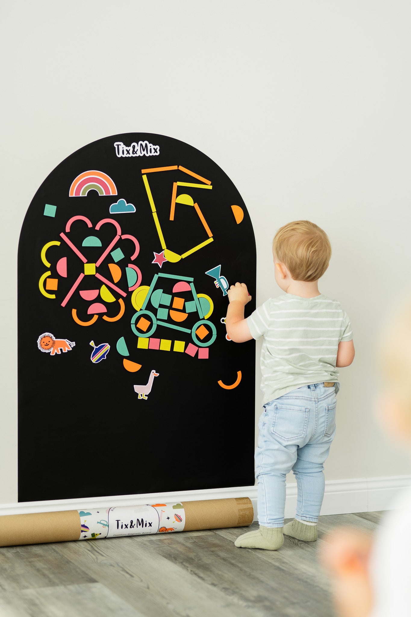 A male toddler playing on a Tix&Mix black magnetic wall decal.