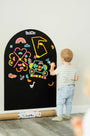 A toddler playing with Rings and Blocks set on Tix&Mix black magnetic wall decal.