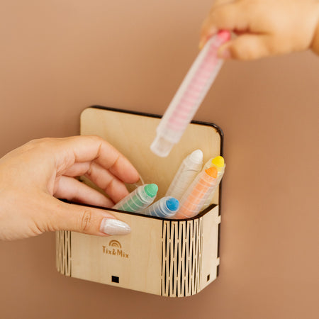 Two hands placing Tix&Mix crayons on a magnetic magic box.