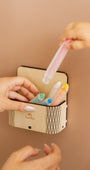 A toddlers hand placing a crayon on a magic box attached to a brown magnetic wall decal.