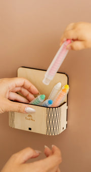 A toddlers hand placing a crayon on a magic box attached to a brown magnetic wall decal.