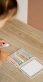A kid grabbing a crayon from a Tix&Mix crayon case located on the floor.