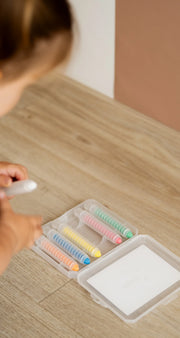 A kid grabbing a crayon from a Tix&Mix crayon case located on the floor.