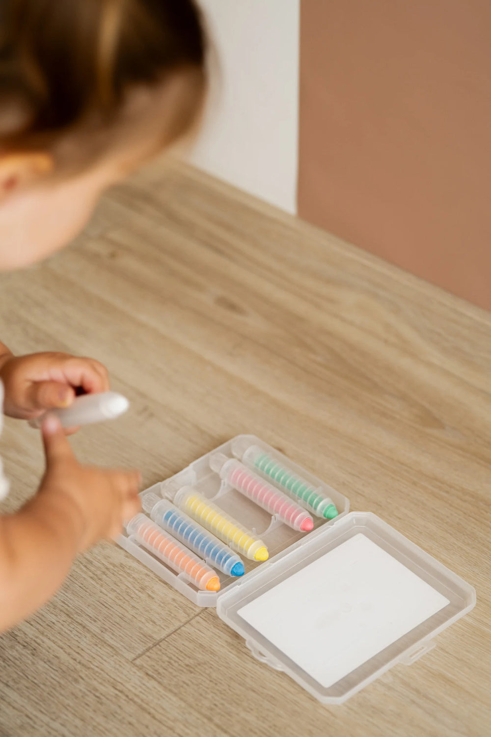 A kid grabbing a crayon from a Tix&Mix crayon case located on the floor.