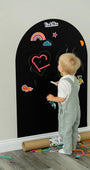 A toddler drawing on a black magnetic wall decal using Tix&Mix crayon.