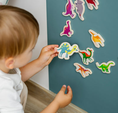 Child playing with colorful dinosaur stickers on a blue wall