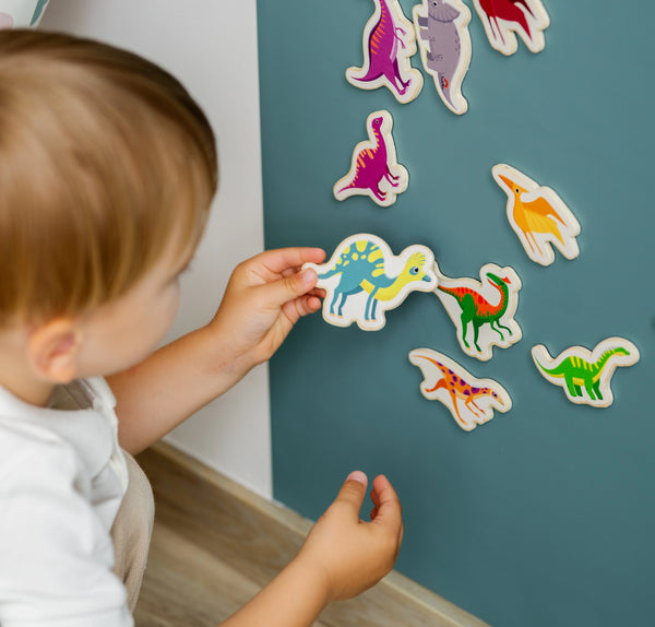 Child playing with colorful dinosaur stickers on a blue wall