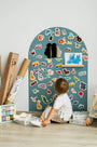 A male toddler looking up at the Tix&Mix cyan magnetic wall decal with magnetic toys placed on it.