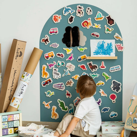 A male toddler looking at the Tix&Mix magnetic toys and accessories placed on a blue dream wall decal.