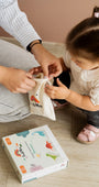 A parent assisting her child unbox a brand new Tix&Mix wooden magnetic dinosaur playset.