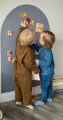 Two toddlers playing with Tix&Mix animals puzzle set on a grey magnetic wall decal.
