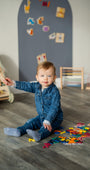 A toddler playing with Tix&Mix magnetic numbers and letters with grey wall decal on the background.