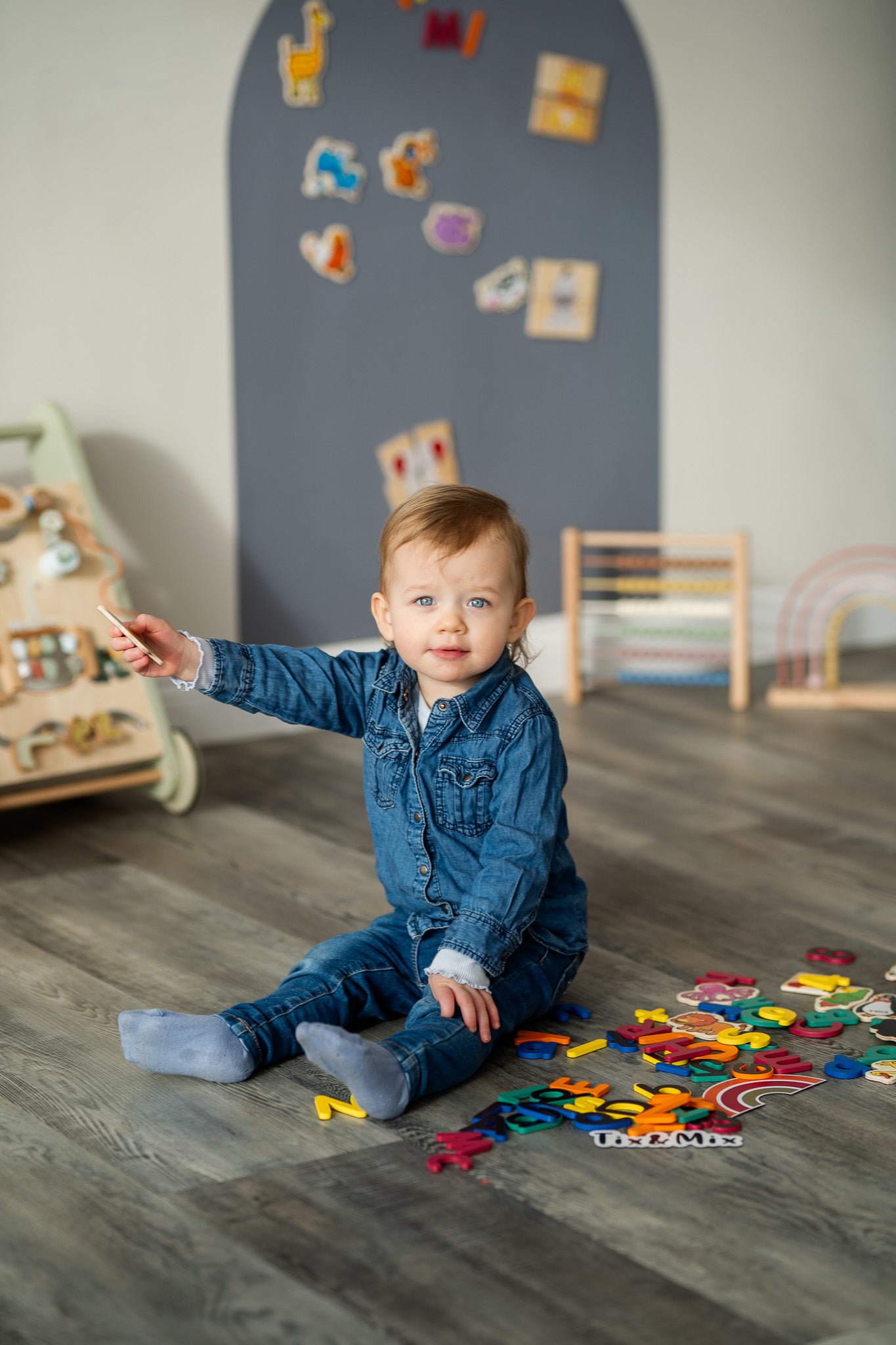 A toddler playing with Tix&Mix magnetic numbers and letters with grey wall decal on the background.