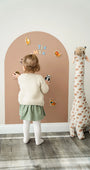 A female toddler playing with magnetic animal toys on a brown wall decal.