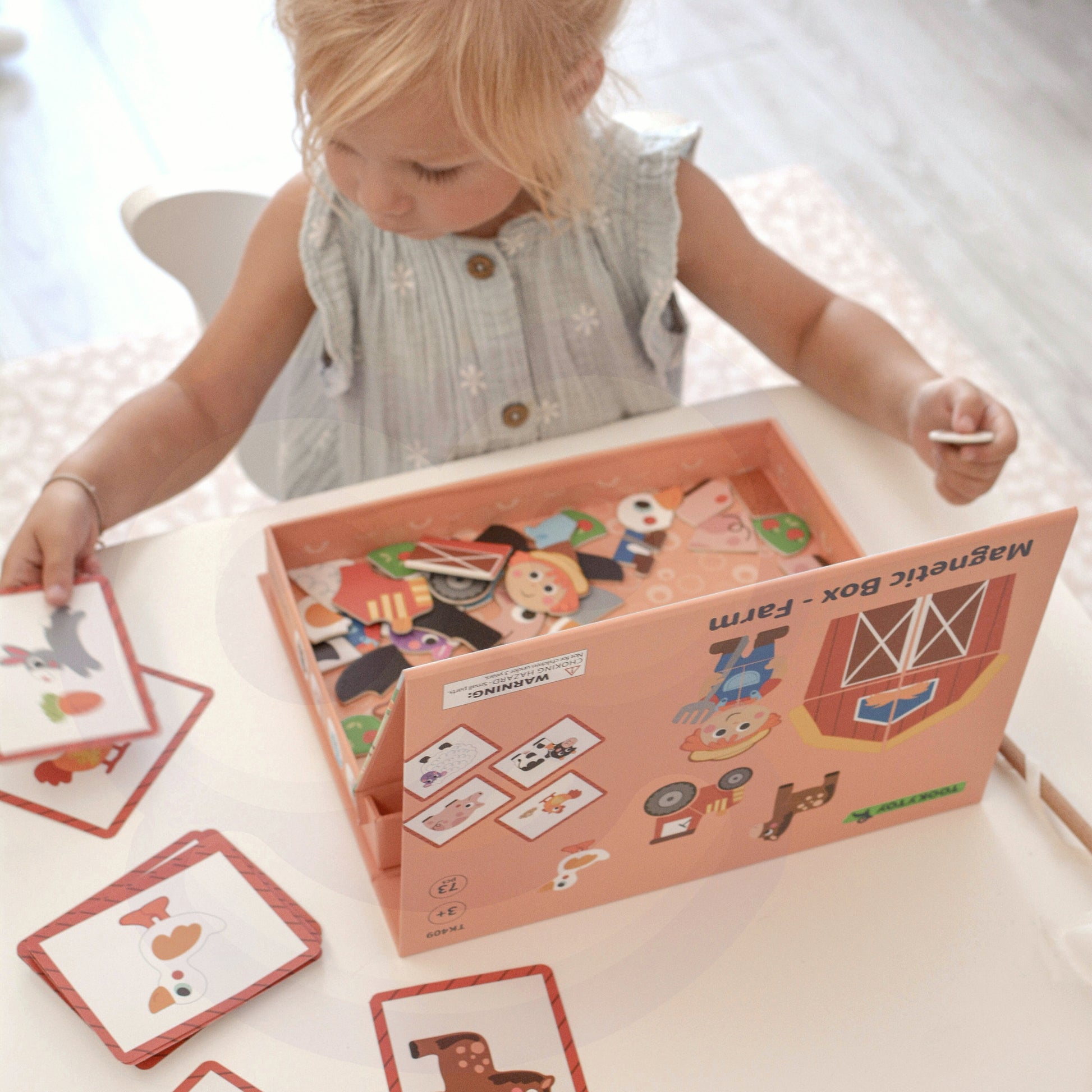 A female toddler busy playing with Tix&Mix magnetic farm toy set.