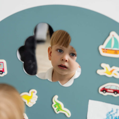 A toddler looking at himself on a Tix&Mix magnetic mirror.