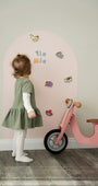 A female toddler playing with Tix&Mix magnetic animals play set on a pink magnetic wall decal.