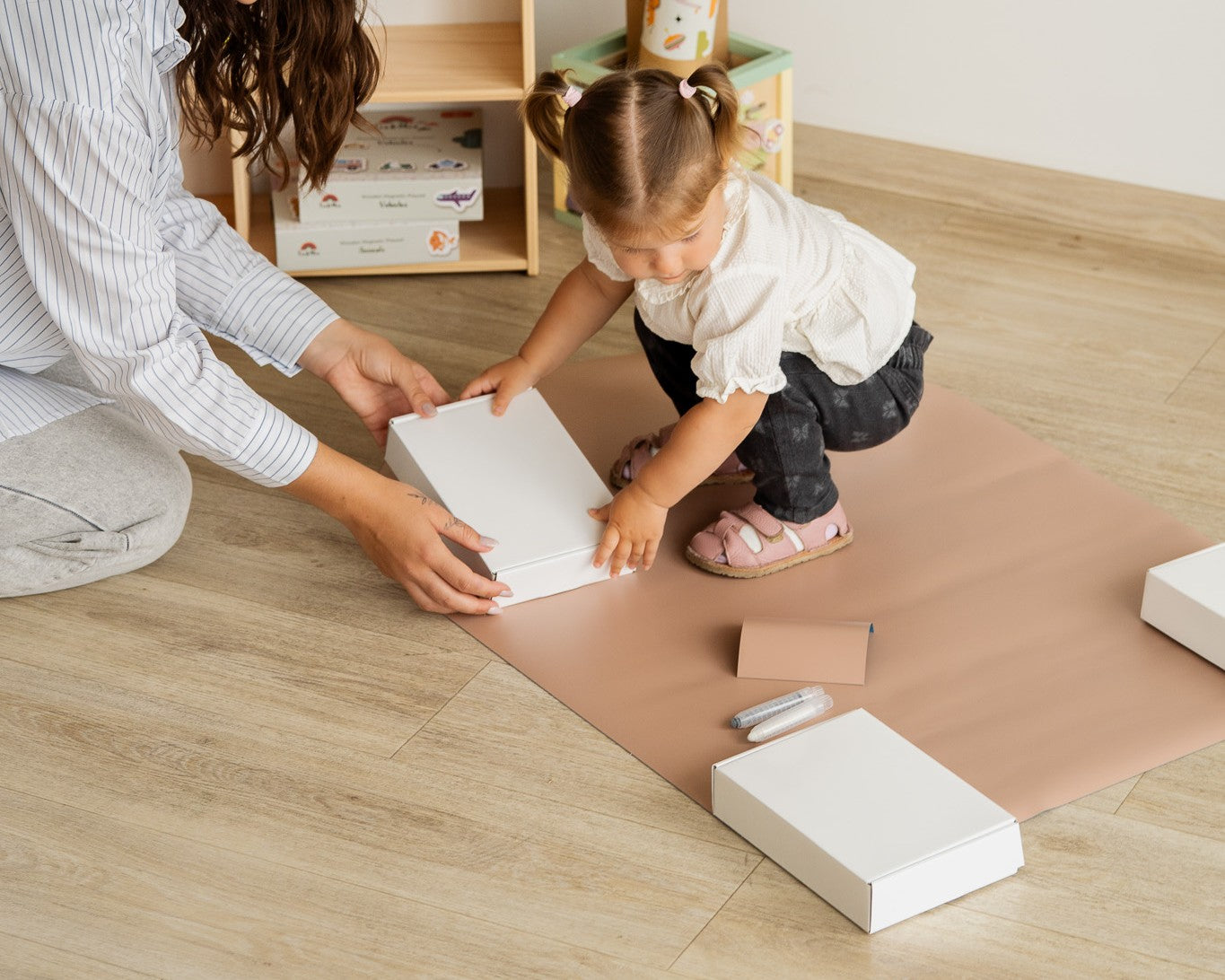 A mother and child unboxing Tix&Mix magnetic toys to be used on magnetic wall board.