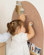 A toddler drawing on a brown magnetic wall decal using a Tix&Mix premium crayon.