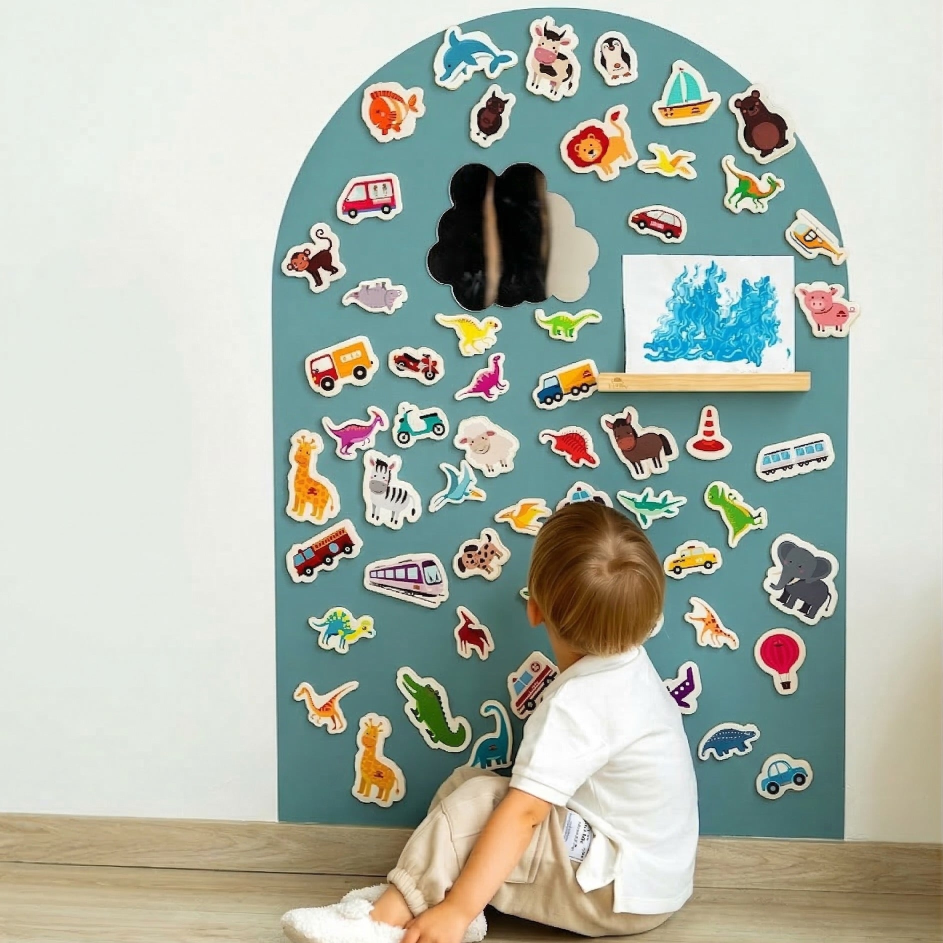 A toddler looking at a Tix&Mix magnetic wall decal in cyan blue color attached on the wall.