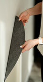 A woman attaching a white magnetic wall decal on a clean white wall.