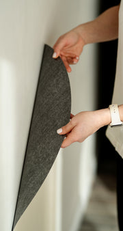 A woman attaching a white magnetic wall decal on a clean white wall.