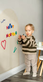 A male toddler playing with Tix&Mix Rings and Blocks play set on a white magnetic wall decal.