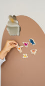 A hand placing Tix&Mix magnetic dinosaur toy on a brown magnetic wall decal.