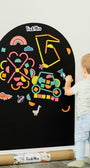 Child drawing on a magnetic wall decal with colorful crayons in a room.