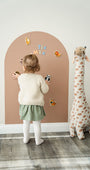 A female toddler playing with Tix&Mix magnetic animals toy set on a premium magnetic wall decal.