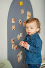 A male toddler playing with Tix&ix animals puzzle toy set on a grey magnetic wall decal.