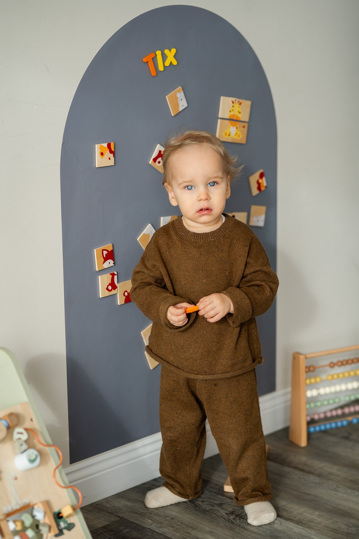 A toddler looking at the camera while playing with Tix&Mix magnetic toys.