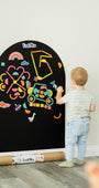 A male toddler playing with Tix&Mix Rings and Blocks Play Kit on a black magnetic wall decal.