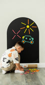 A male kid playing with Tix&Mix rings and blocks play kit on a black magnetic wall decal.