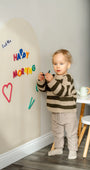 A male toddler playing with Tix&Mix Rings and Blocks set on a white wall decal.