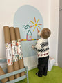 A toddler playing with Tix&Mix Rings and Blocks set on a blue dream wall decal with new decal rolls on the side.