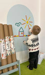 A toddler playing with Tix&Mix Rings and Blocks set on a blue dream wall decal with new decal rolls on the side.